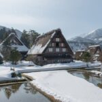 雪に覆われた白川郷の合掌造りの家々と冬の山