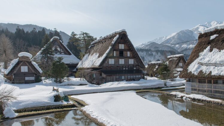 雪に覆われた白川郷の合掌造りの家々と冬の山